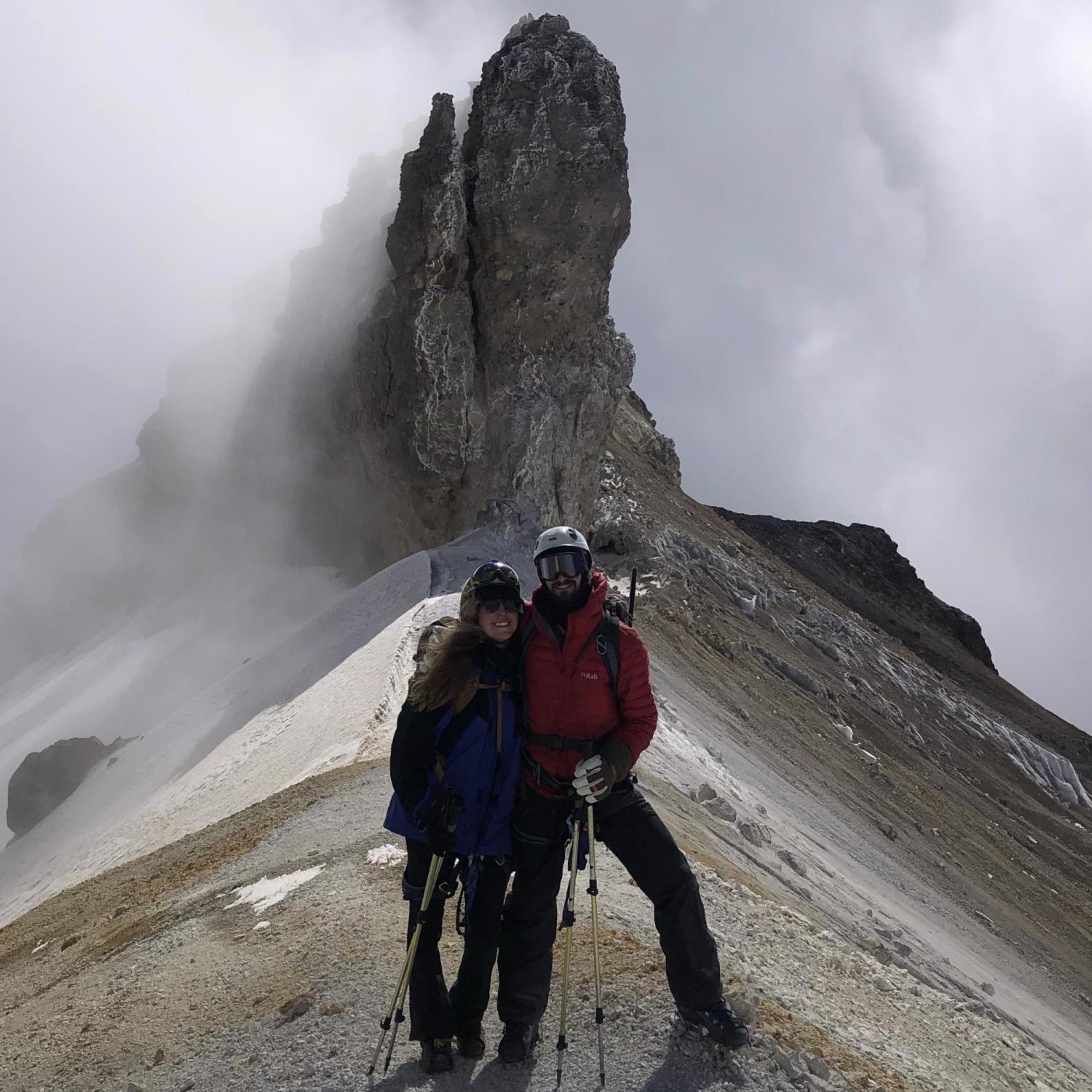 Aaron Friedland and friend posing in front of a rocky structure on a hike.