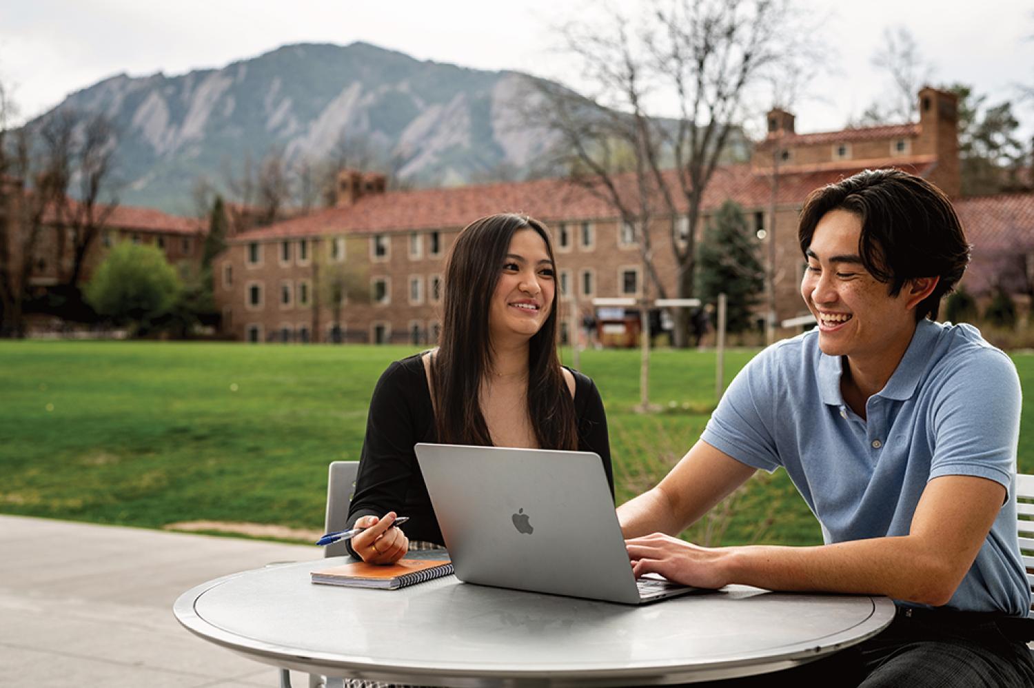 Julie Huang and Kevin Nguyen laugh while meeting at an outdoor table