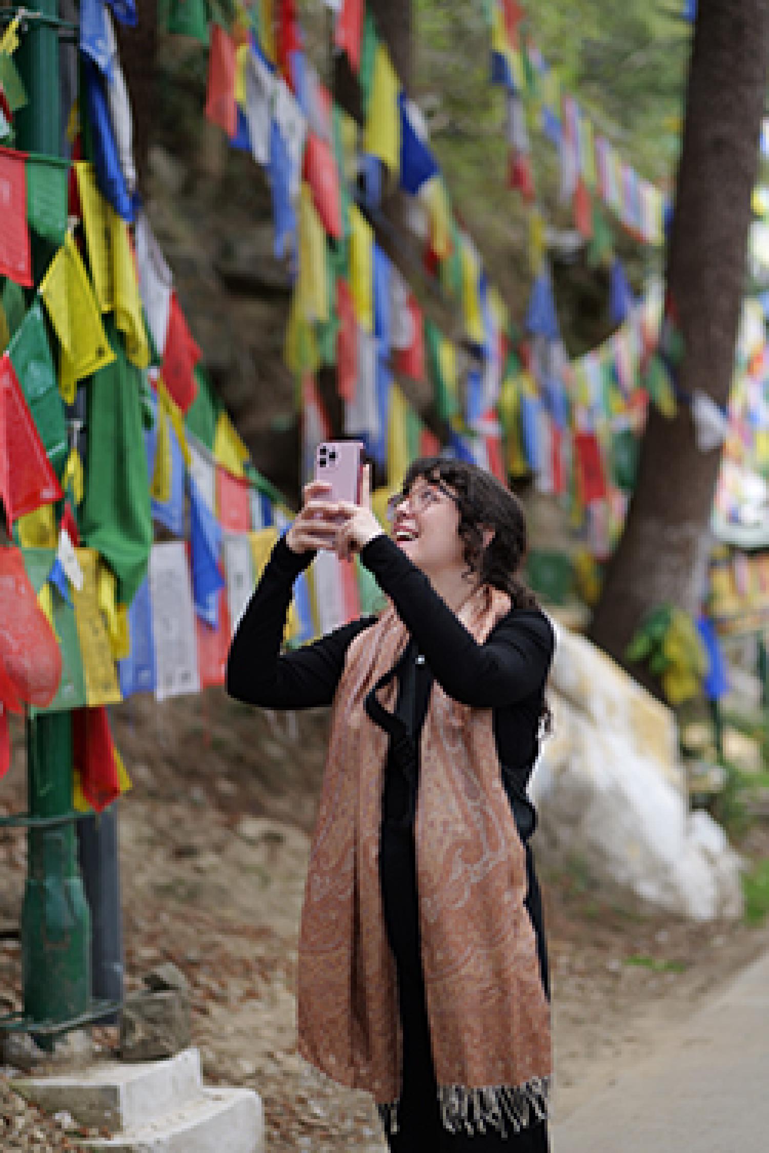 Nikki Bechtold holds up her phone to take a photo of the colorful flags surrounding her