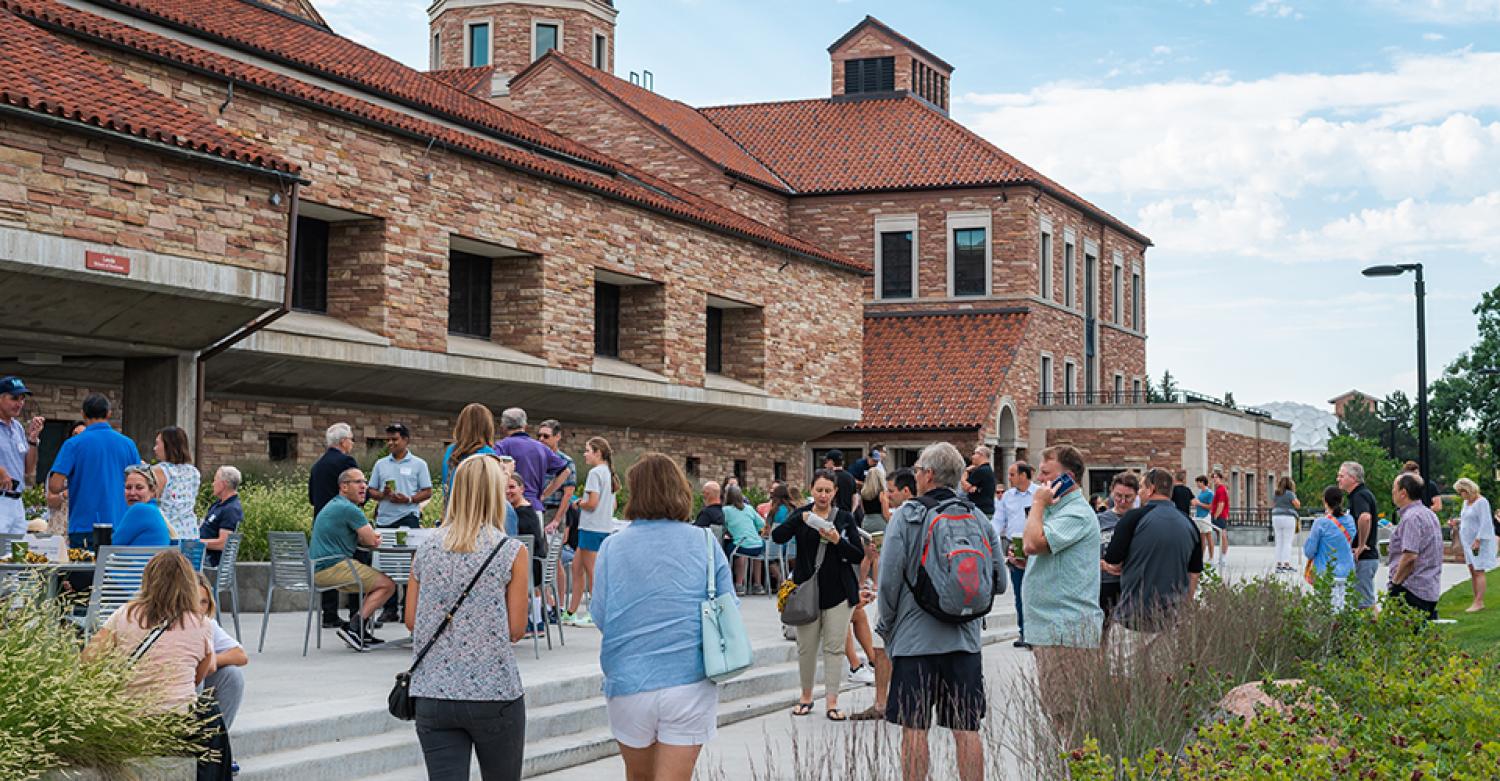 The Rustandy Building with students and parents enjoying the weather outdoors.