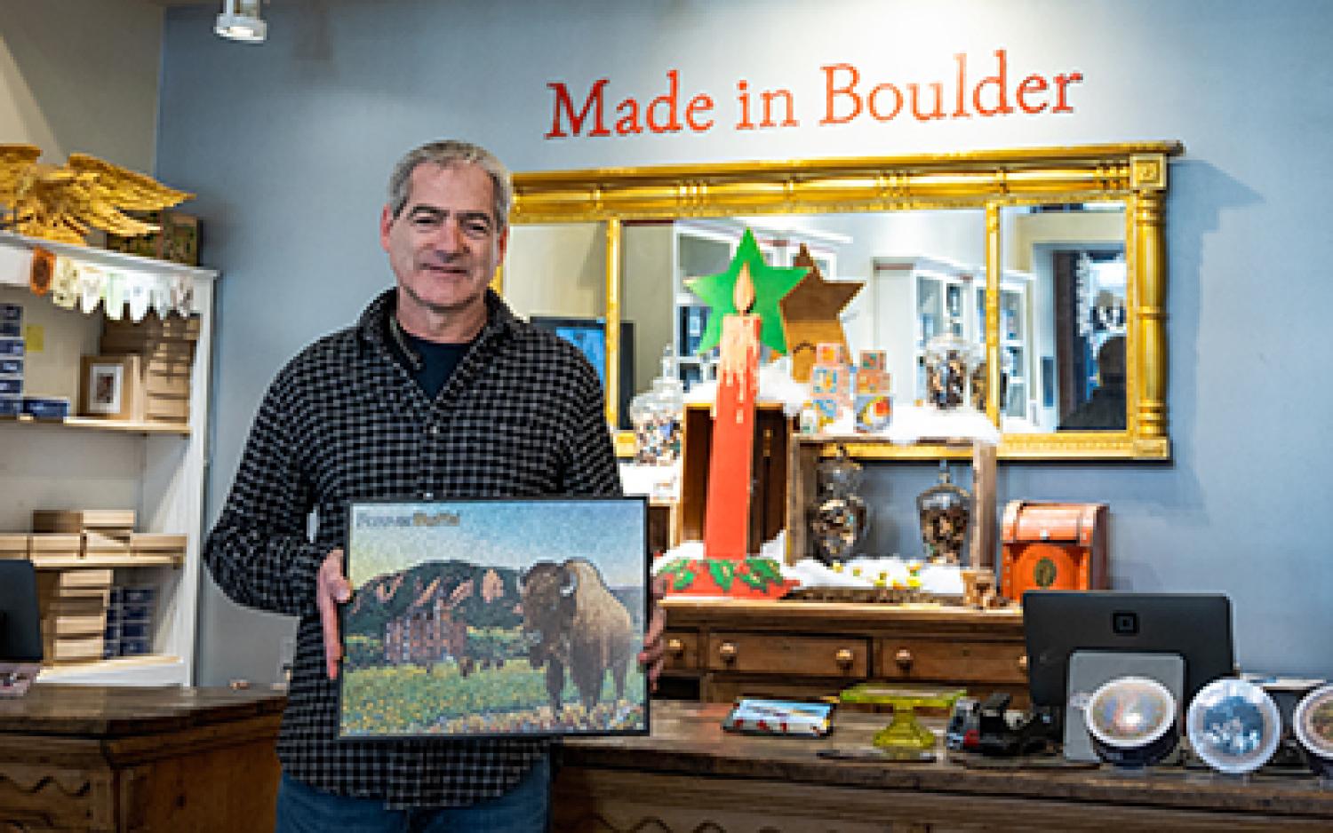 Chris Wirth folds a framed Forever Buffs puzzle in his Boulder showroom.
