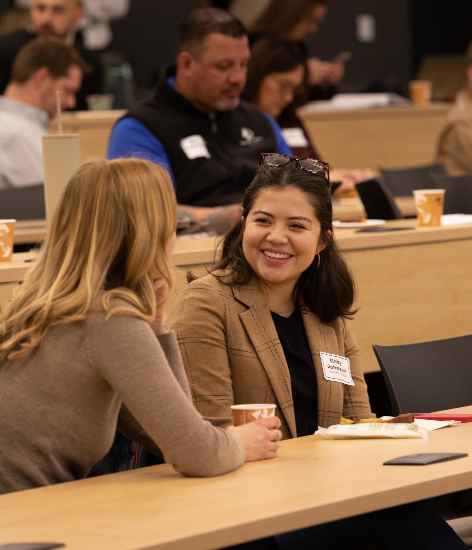 two professionals smiling and talking to each other in a lecture hall