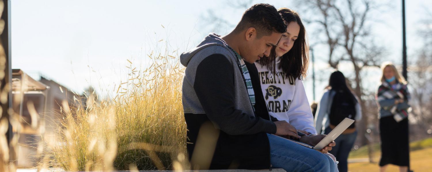 Two students working together outside.