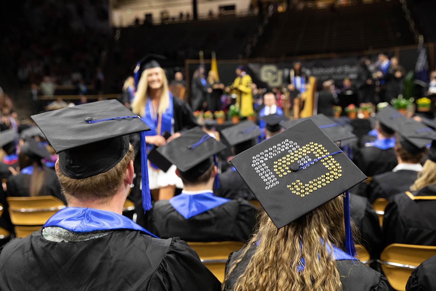 Students' decorate grad caps in the audience at a graduation ceremony.