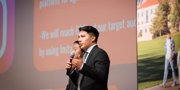 A student in the Business Leadership program speaks into a microphone while delivering a presentation as part of the program.