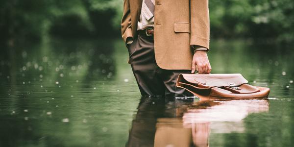 A businessman stands up to his calves in water. 