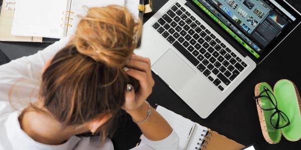 Overhead shot of a woman working in a messy space with her head in her hand.