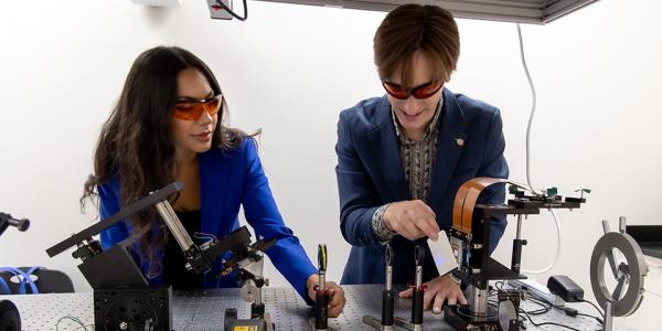 Camila and Johnny working with a laser in their 3D printing lab.