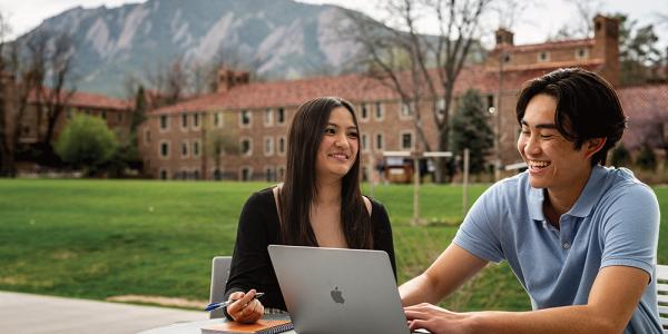 Julie Huang and Kevin Nguyen share a laugh while meeting at an outdoor table on CU's campus.