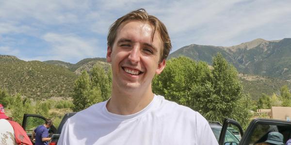 Connor stands outside with the Flatirons in the background.