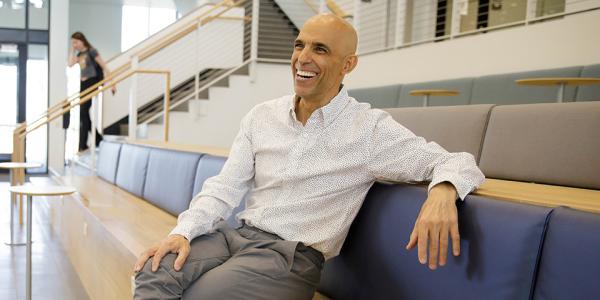 Rico laughs while sitting in a casual work area in the Rustandy Building.