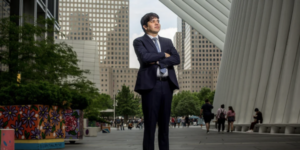 Wearing a suit, Diego Alvarez poses in Lower Manhattan