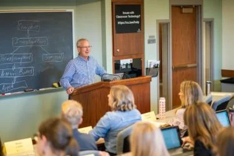 Photo of instructor giving a lecture at the front of a classroom