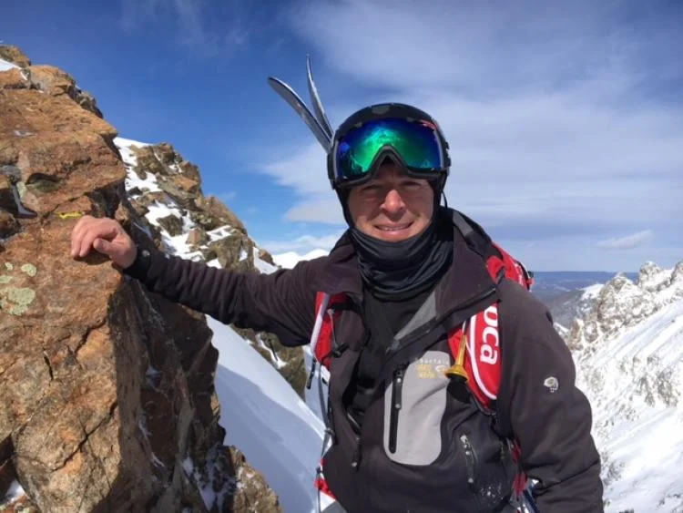 Rob Mossman poses on a mountainside wearing ski gear