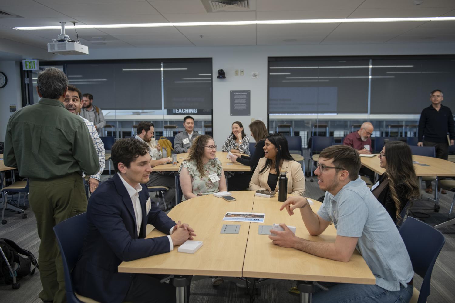 A room full of students, faculty, staff and alumni engage in coversation