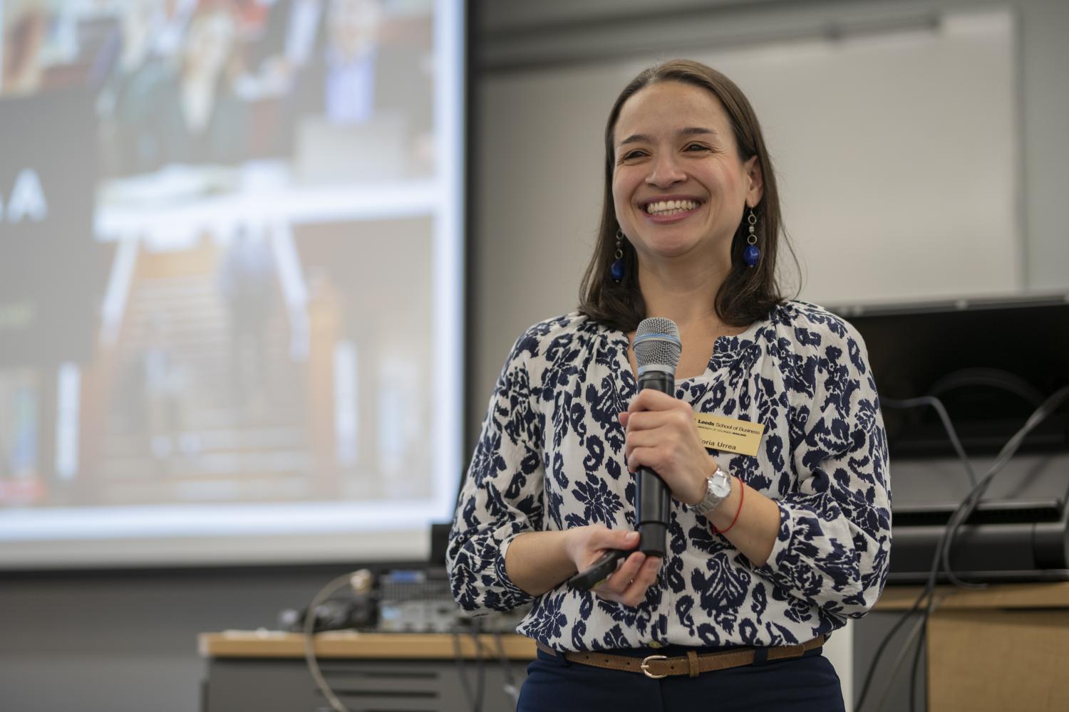 Gloria Urrea smiles while holding a mic