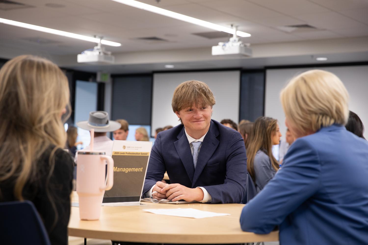 A student in professional attire smiles while in conversation at the Leeds Professionalism Summit.