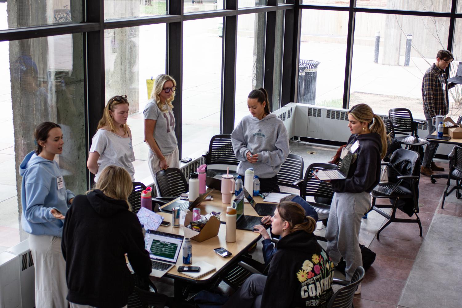 Students gather around a table while participating in the BeWIT Hackathon