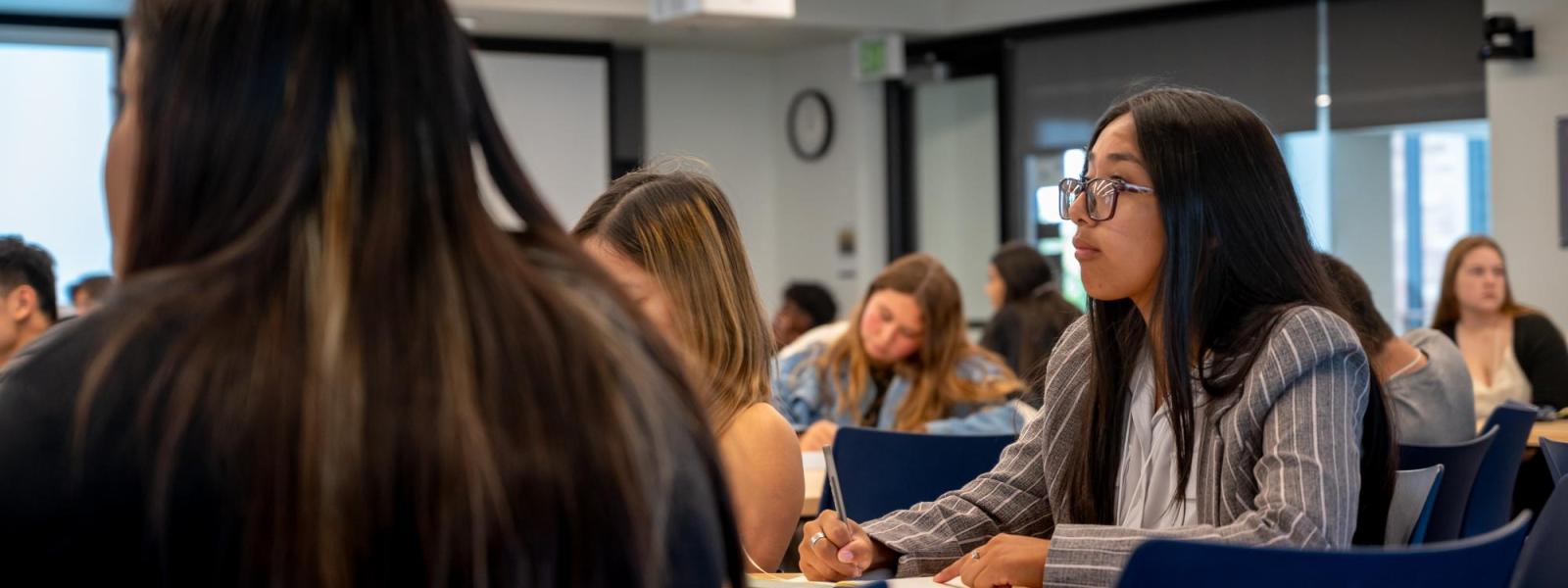 A female student is taking notes during a Business at a Glance academic session.