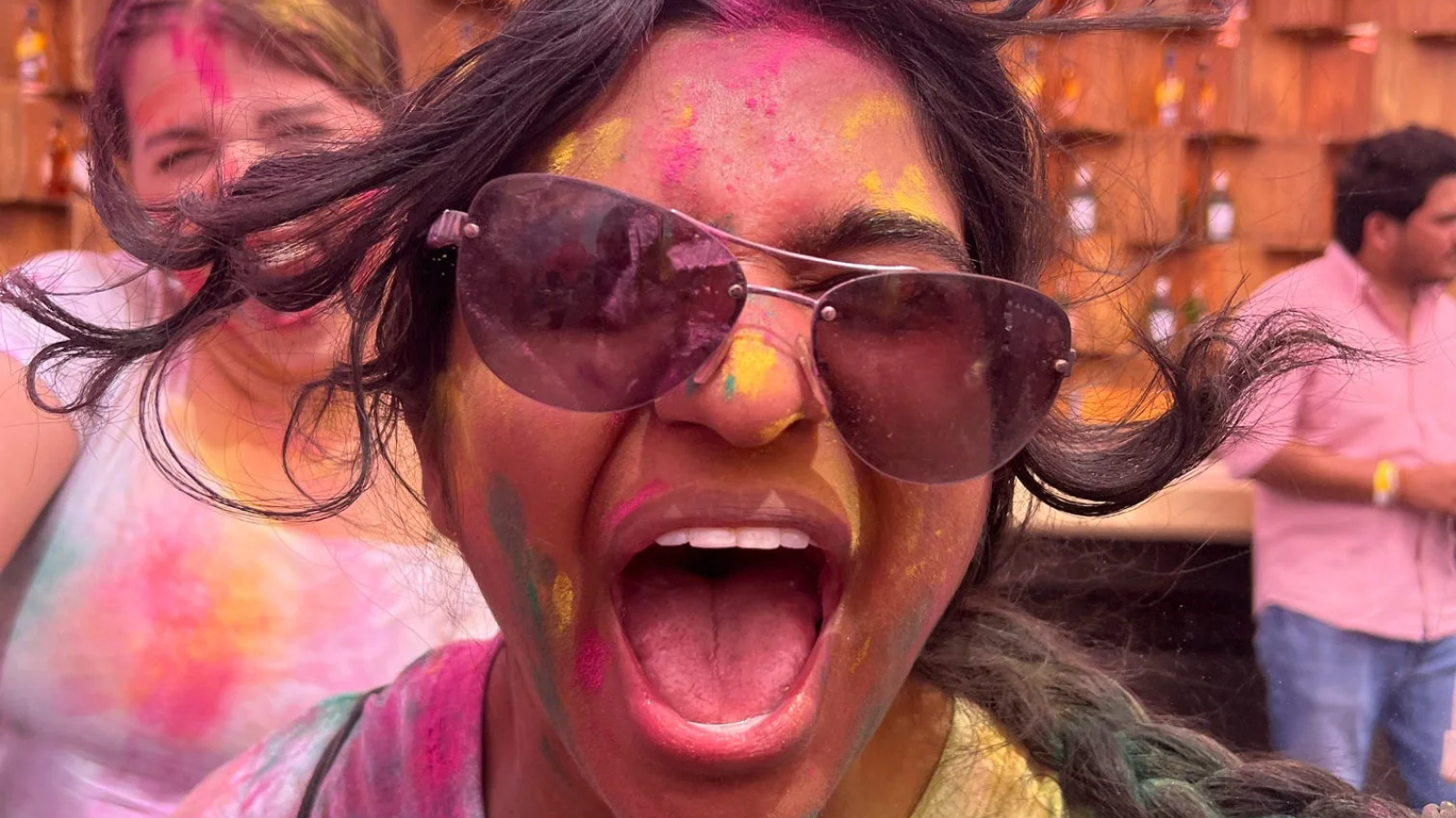 A student covered in paint yells in excitement during a Holi celebration
