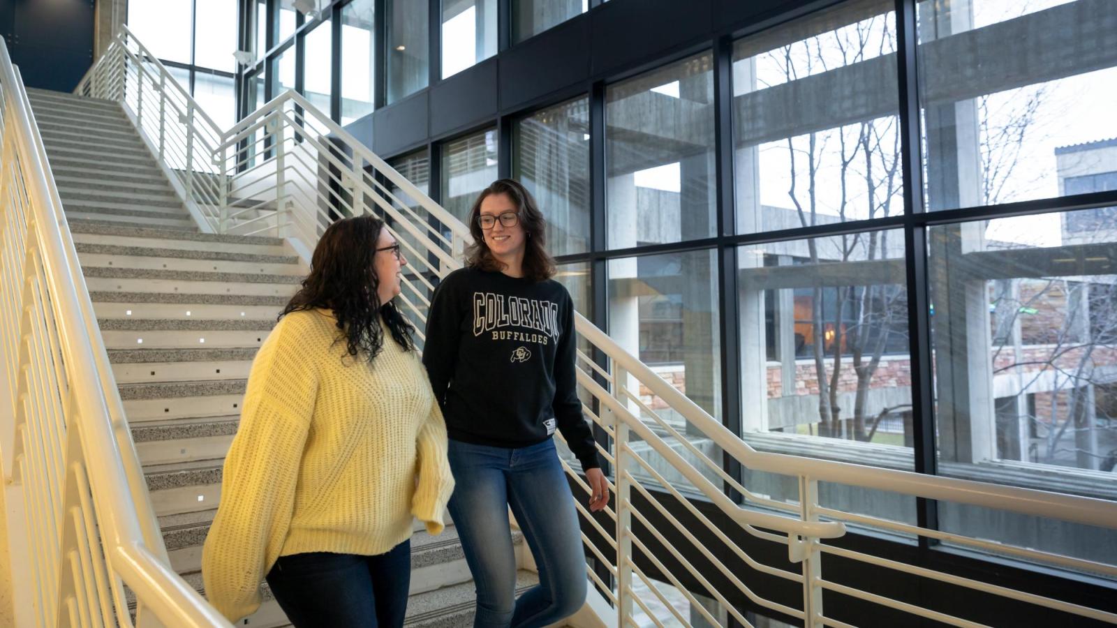 Two students in the Peer to Peer mentor program walk down the stairs.