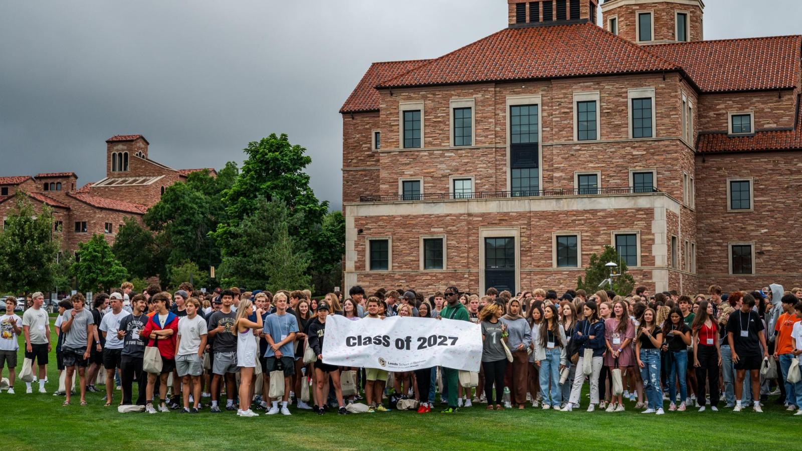 Students in Leeds Class of 2027 pose with a banner in front of the Koelbel Building.