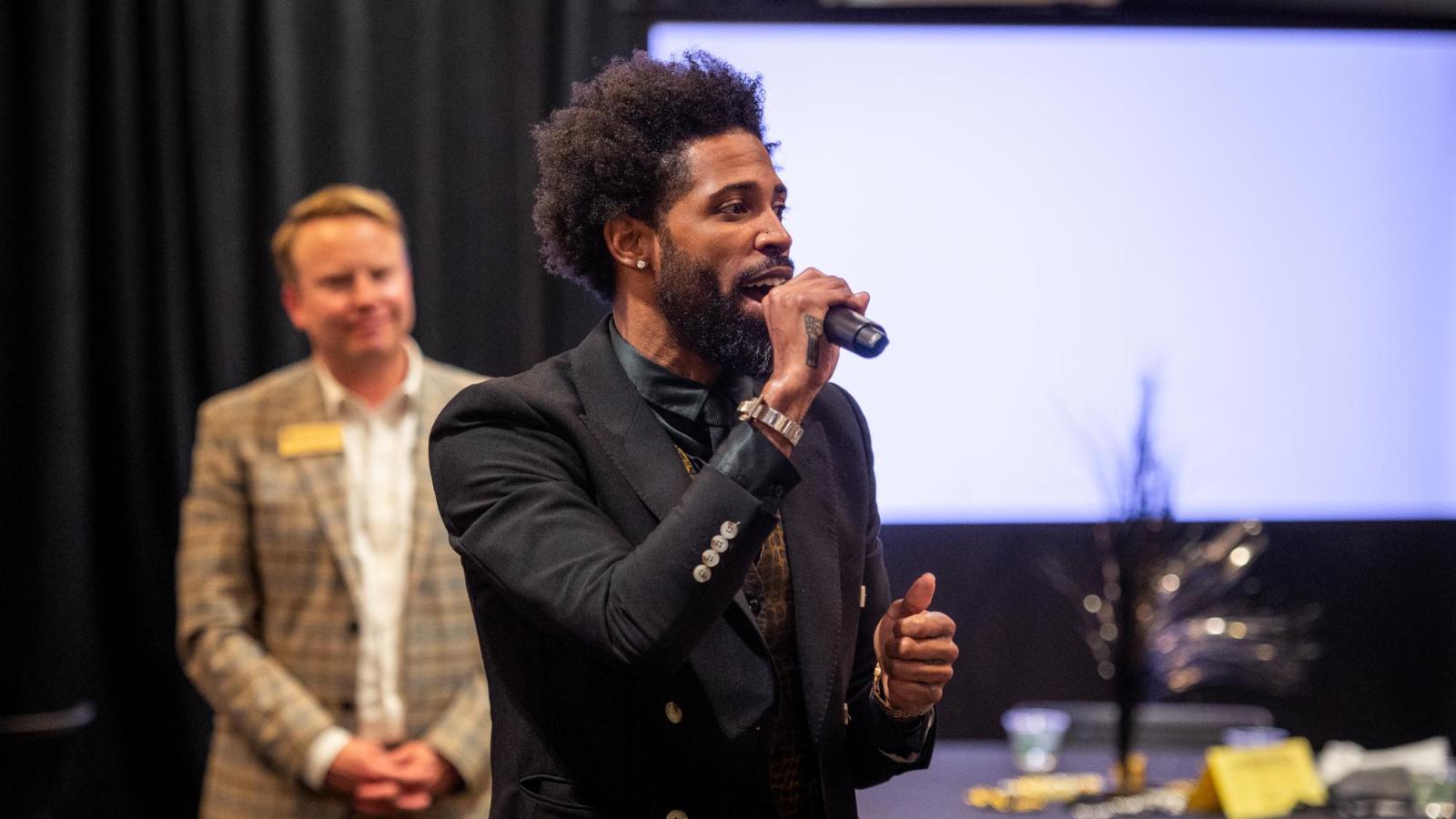 A person speaks into a microphone at the Barney Ford Diversity Fundraiser.