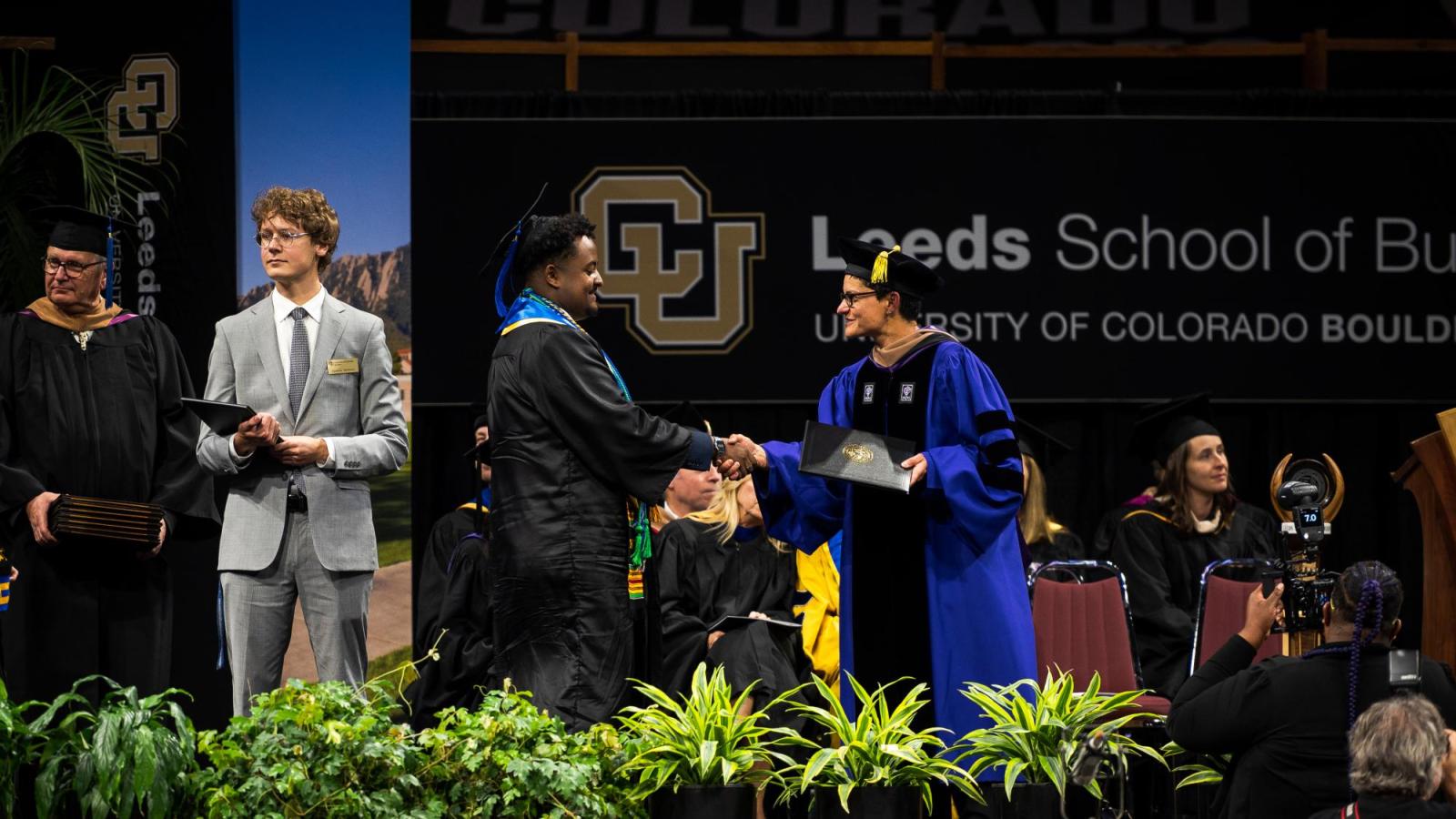 Then Acting Dean Yonca Ertimur shakes hands with a student as they cross the stage during graduation.