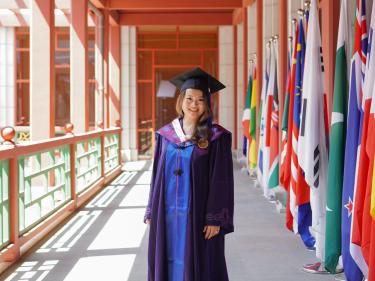 Jessica Yan poses in regalia during her master's program graduation.