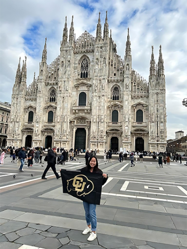 Anna holding a CU Boulder flag at Duomo in Milan, Italy