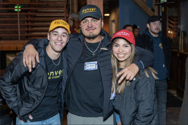 Two men and a woman wearing Denver Pub Crawl merch smile in a group photo