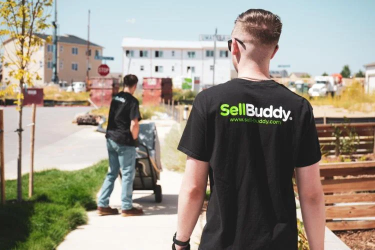 A man walks away from camera wearing a black SellBuddy T-shirt