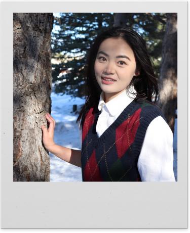Qian Su poses outside next to a tree in a photo with a polaroid-style frame