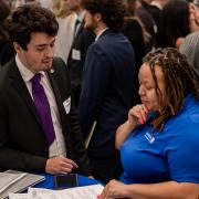 A male student and female recruiter review a resume together at a networking event in the Rustandy Building.