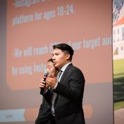 A student in the Business Leadership program speaks into a microphone while delivering a presentation as part of the program.