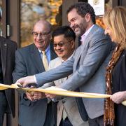 Five people in professional dress cut the ribbon on a new building on the CU Boulder campus.