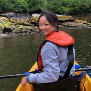 Grace Trahan looks back while paddling a kayak.