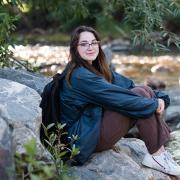 Julie Gentile sits beside a creek in the middle of the woods.