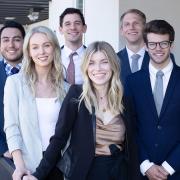 Four male and two female students pose as a group in professional dress.