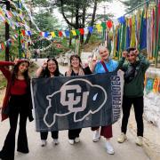 Students pose with a CU flag while holding up Buff horns