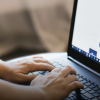 A closeup of a person's hands typing on a laptop