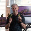 Russell Jeans poses with his parrots in front of a home work station