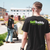 A man walks away from camera wearing a black SellBuddy T-shirt