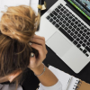 Woman leans forward over her work seemingly stressed out