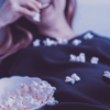 A woman eats popcorn while sitting on the couch holding a remote