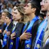 Students in regalia place their hands over their hearts during the national anthem.
