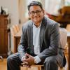 Ashish Kothari, in business attire, smiles in his home.