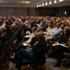 Crowd shot from the Business Economic Forum. Hundreds of professionals are gathered in a ballroom.