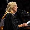 Jay Parry, in her regalia, speaks to the graduates at the podium of the CU Events Center.
