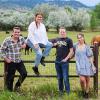 Four students stand along a fence, where cows graze in a pasture.